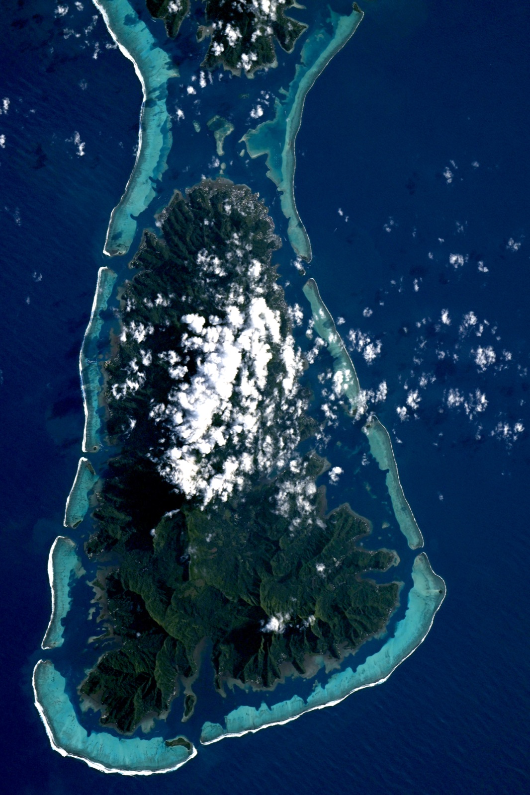 Raiatea, French Polynesia, photographed from the International Space Station: a high volcanic island ringed by its barrier reef and lagoon. Image: ESA/NASA – S. Adenot.